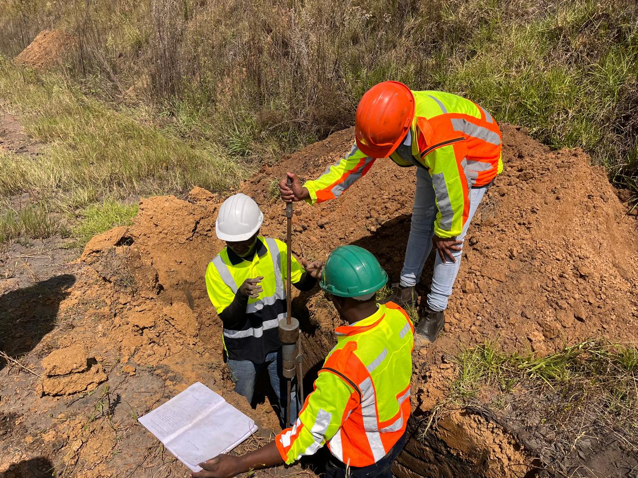 Team members working around an excavated test pit